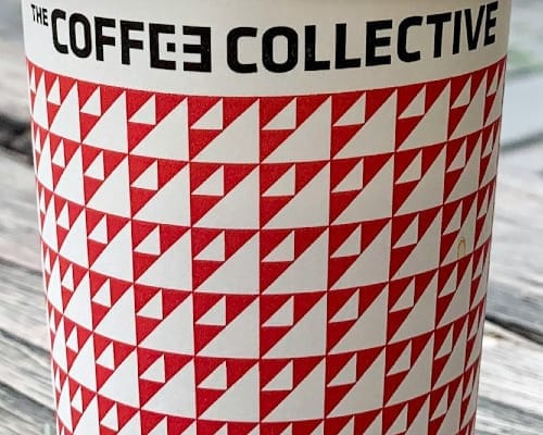 close up of red and white coffe cup with Coffee Collective spelled in black across the top